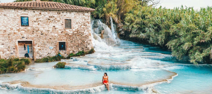 woman sitting next to a house w natural hot spring